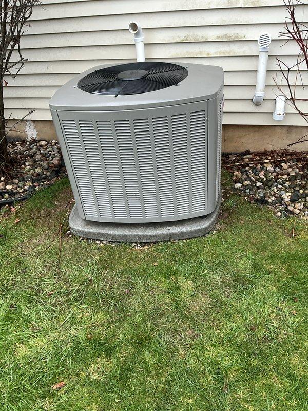 Completed routine annual maintenance on residential air conditioning system. Performed comprehensive tune-up on 1-year-old AC unit located on exterior concrete pad. Inspected condenser unit housing, verified proper clearance from structure, and confirmed secure mounting on level pad. Checked refrigerant lines and PVC condensate drainage system for proper installation and function. Cleaned condenser coils and removed debris from unit exterior and surrounding area. Inspected fan motor, blades, and protective grille for proper operation and structural integrity. Verified electrical connections and conduit are secure. Tested system startup and operational parameters. Unit found in good working condition with no issues identified. All components functioning within manufacturer specifications. System ready for cooling season operation.