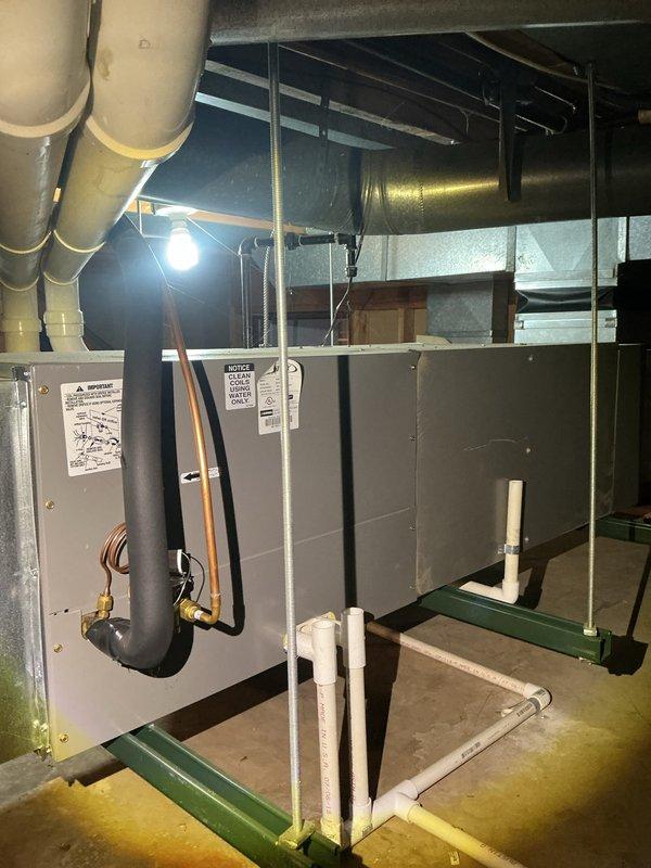 # HVAC Maintenance - ACM Service Completed

Performed comprehensive Air Care Cooling maintenance on residential HVAC system located in basement mechanical room. Conducted thorough inspection of air handling unit mounted on elevated green support rails with associated ductwork and piping systems.

## Equipment Inspection and Findings

Inspected primary air handling unit and evaporator coil assembly. Visual examination revealed significant biological growth present on evaporator coil surfaces, evidenced by yellow-green substance covering portions of the aluminum fin array, particularly concentrated along top edges and distributed across multiple sections of the coil. This growth pattern indicates moisture accumulation and potential drainage concerns that can reduce system efficiency and indoor air quality.

Verified all refrigerant line connections, including copper lines with brass fittings and associated black insulation material. Examined PVC condensate drainage piping with curved elb