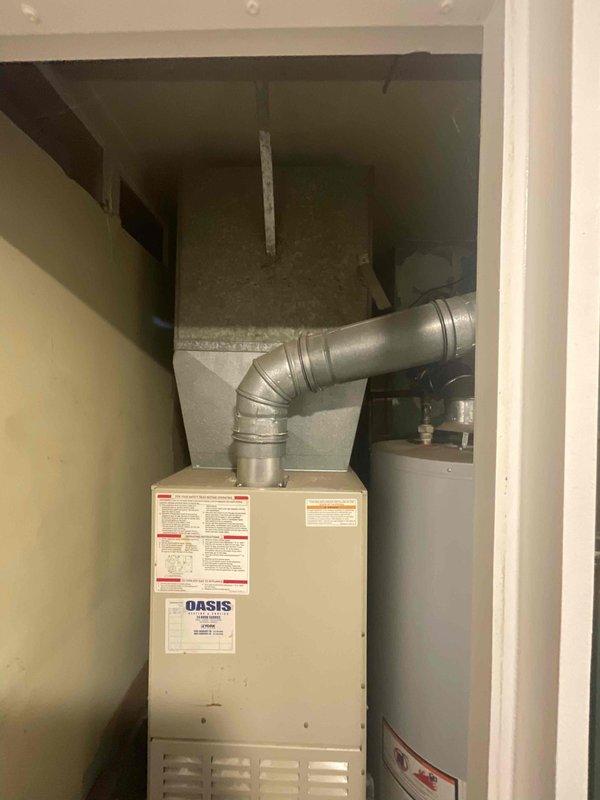 Conducted comprehensive assessment of aging HVAC system for replacement estimate, including 31-year-old furnace located in interior utility closet and outdoor central air conditioning condenser unit dating to approximately 1995. Documented existing equipment conditions through detailed photography, noting the Oasis-branded furnace with metallic ductwork configuration and water heater proximity constraints in confined mechanical room space. Evaluated exterior AC condenser unit showing significant weathering, rust formation, and discoloration consistent with extended service life, along with associated PVC drainage line routing and concrete pad placement. Provided replacement options and prepared estimate for complete system upgrade to address end-of-life equipment requiring immediate attention.