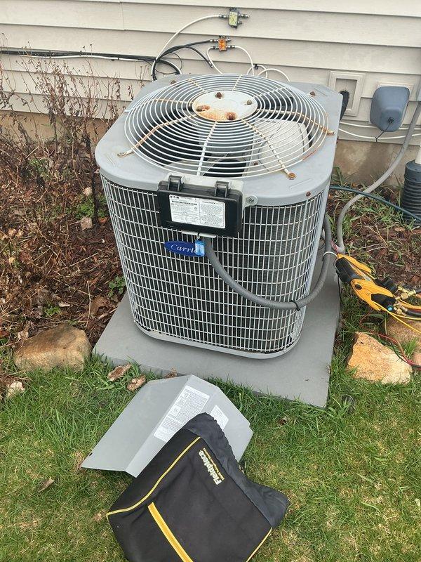 Completed comprehensive AC tune-up on 15-year-old Carrier outdoor condensing unit. Performed standard maintenance protocol including inspection of refrigerant lines, electrical connections, and conduit routing; verified proper operation of compressor and condenser fan motor; cleaned condenser coil and checked airflow through mesh grille. Unit operational and functioning within normal parameters despite visible exterior weathering and rust staining on fan grille assembly, which is cosmetic and does not affect performance at this time.