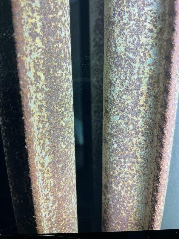 Responded to no-heat call on 15-year-old forced air furnace system that had experienced flooding. Upon arrival, conducted thorough inspection of unit and surrounding components. Found extensive corrosion and oxidation on metal piping throughout the system, indicating prolonged water exposure and moisture damage. Documented internal components including water heater tank, mounting brackets, PVC piping with connections, and electrical wiring assembly. Assessed condition of all visible components including motor, pump unit, and electrical connections with wire nuts. Photographed corroded vertical pipes displaying heavy rust and oxidation patterns, as well as internal mechanical systems showing dust accumulation and age-related wear. System confirmed non-operational at time of inspection due to flood damage.