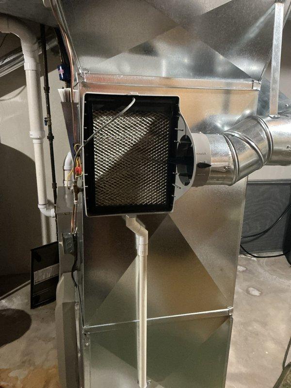 Responded to service call for non-operational humidifier with no water flow through unit. Upon arrival, inspected residential HVAC system including furnace and Bryant air handler assembly in basement mechanical room. Removed furnace access panel to examine internal components, wiring connections, and blower assembly. Verified humidifier installation, water supply line connections, and drainage system including PVC condensate piping. Inspected ductwork connections and air filtration system to ensure proper airflow through humidifier pad. Diagnosed issue preventing water distribution through humidifier media and restored unit to operational status.