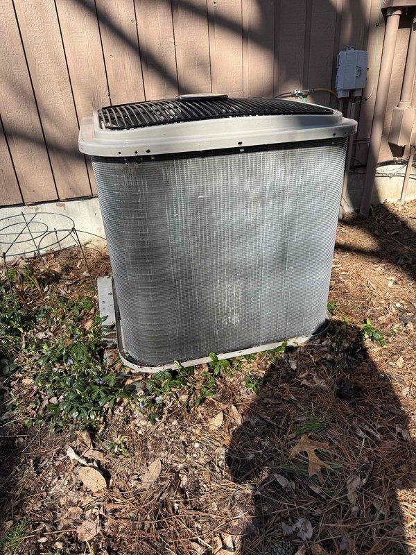 Completed annual cooling maintenance on outdoor condenser unit. Inspected system components and noted significant dirt and debris accumulation on condenser coils and fins. Documented unit condition with photos showing weathering, algae growth on protective grille, and organic debris around equipment pad. Filter replacement required as indicated on service order.