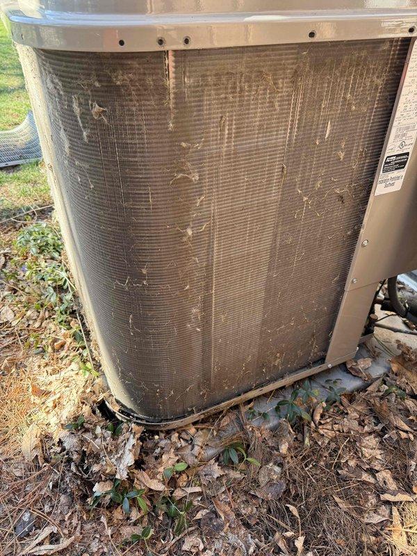 Completed annual cooling maintenance on outdoor condenser unit. Inspected system components and noted significant dirt and debris accumulation on condenser coils and fins. Documented unit condition with photos showing weathering, algae growth on protective grille, and organic debris around equipment pad. Filter replacement required as indicated on service order.