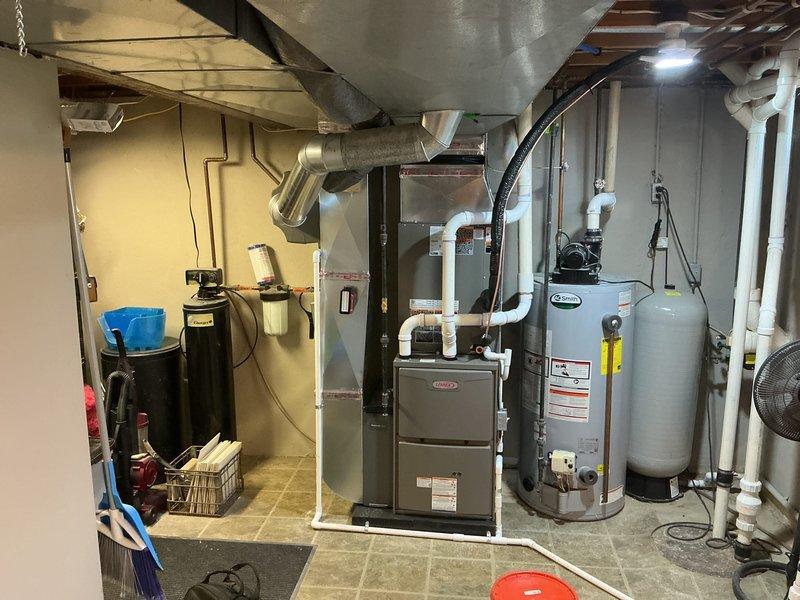 Completed full HVAC system installation including new gas furnace in basement mechanical room and outdoor condensing unit. Installed furnace with proper PVC venting routed upward, connected to existing ductwork system, and positioned unit adjacent to water heater. Installed outdoor condensing unit on pad with river rock base, ran refrigerant lines and electrical conduit to exterior wall penetration, and connected system components for complete heating and cooling operation.