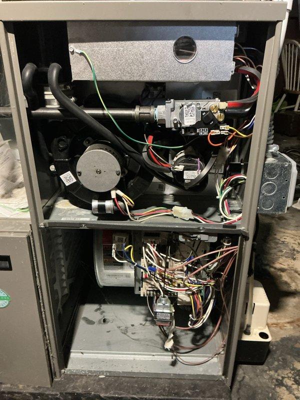 Responded to no-heat call for 4-year-old gas furnace and water heater both reported non-operational, with basement flooding present. Upon arrival, conducted diagnostic inspection of furnace system with cabinet access panel removed to assess internal components including heat exchanger, gas valve assembly, blower motor, and electrical connections. Verified all wire harnesses, safety controls, and mechanical components for proper operation. Inspected return air grille and ventilation system for adequate airflow. Documented system condition with interior cabinet photography showing gas valve, ignition components, heat exchanger assembly, and blower motor configuration. Basement flooding condition noted as potential contributing factor to equipment malfunction requiring water mitigation prior to full system restoration.