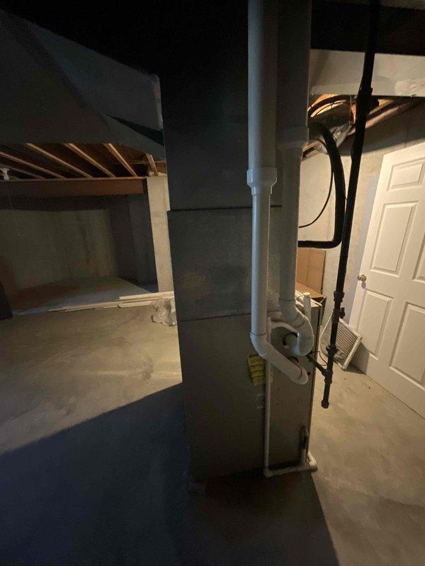 Provided estimate for furnace replacement in basement location. Existing unit is non-operational and has reached end of service life at 20-25 years old. Assessed current HVAC system with light blue painted ductwork extending vertically through exposed ceiling joists. Documented installation area including concrete block walls, concrete flooring, and existing copper piping infrastructure to determine proper equipment sizing and installation requirements for replacement system.