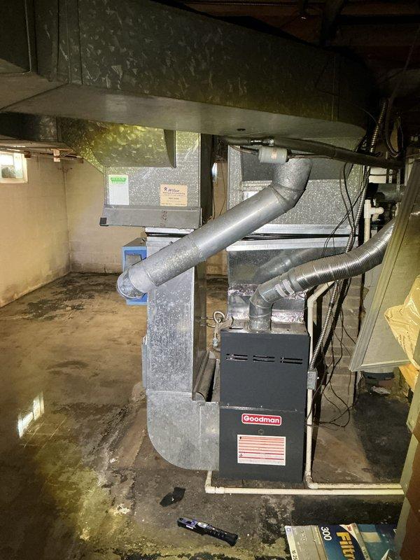 Completed routine Air Care Cooling maintenance on Goodman furnace system in basement mechanical room. Performed standard ACM inspection protocol including visual assessment of unit condition, ductwork connections, and surrounding utility space. All system components photographed and documented, with flexible ductwork and mechanical connections verified for proper installation and secure attachment to primary HVAC equipment.