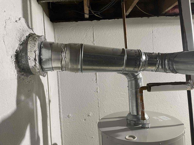 Completed installation of a 40-gallon Bradford White tanked water heater in residential basement utility room. Connected all supply and discharge plumbing lines using copper piping with galvanized fittings, installed gas control valve and connections at base of unit, and secured proper venting with metallic duct work penetrating exterior wall with appropriate sealing. Instructed customer on proper water heater lighting procedures, noting water service would remain off during installation period pending permit approval and final inspection.