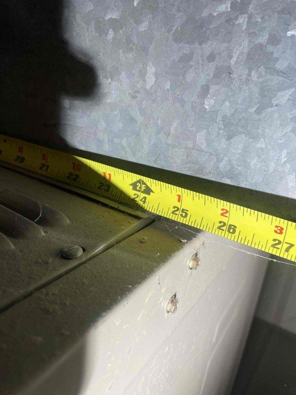 Conducted on-site assessment for air conditioning replacement estimate on 50-year-old unit currently located in laundry room. Existing system is operational but has reached end of serviceable life span. Performed measurements of existing ductwork opening, documenting 2.5-inch clearances and evaluating installation access points within confined mechanical space showing typical wear and dust accumulation on metal components and surrounding surfaces.