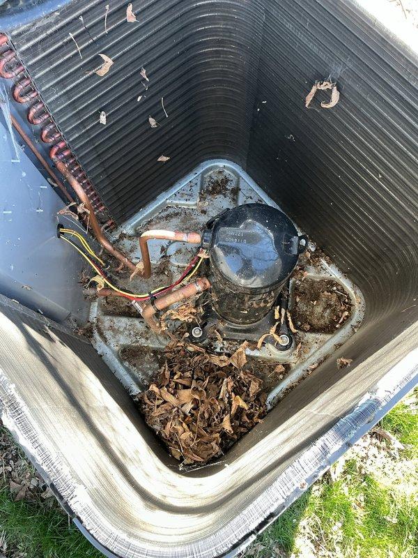 Performed comprehensive ComfortGuard maintenance package on residential HVAC system. Addressed specialty service request for high-efficiency filter replacement and evaporator pad servicing. Inspected outdoor heat pump unit and identified significant organic debris accumulation in base pan around compressor and coil assembly, including decomposed leaf matter and moisture retention indicating potential drainage concerns. Removed accumulated debris, cleaned unit interior, and verified proper condensate drainage. Examined refrigerant lines showing minor surface oxidation consistent with normal weathering. Replaced air filtration media and evaporator humidifier pad as requested. Conducted visual inspection of water heater and associated mechanical systems in utility area. All components operational upon completion of maintenance service.