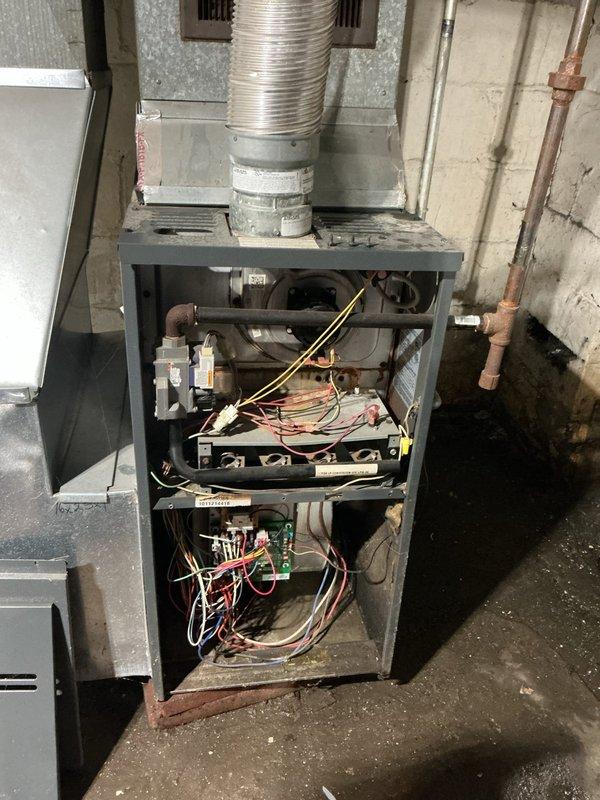 Responded to service call for 15-year-old furnace leaking water in basement installation. Upon inspection, removed front access panel and examined internal components including heat exchanger, burner assembly, blower motor housing, and drainage system. Identified source of water leak and assessed condition of all related components. Performed diagnostic evaluation of condensate drain system, secondary drain pan if equipped, and checked for potential heat exchanger cracks or condensation issues common in aging furnace units. Inspected electrical connections, control board, and blower assembly for proper operation and any moisture damage. Documented equipment condition with detailed photographs showing burner compartment, wiring configuration, blower motor assembly, and overall unit condition for service records.