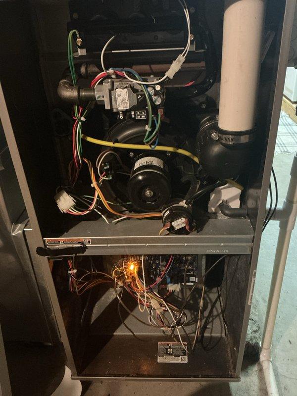 Completed comprehensive annual heating and cooling maintenance on a 10-year-old residential furnace system located in basement installation. Performed full system inspection with access panels removed to evaluate all internal mechanical and electrical components including blower motor assembly, control board, burner compartment, heat exchanger, and gas valve operation. Verified proper pilot light ignition and flame characteristics. Inspected all electrical connections and wiring harnesses for signs of wear or deterioration. Examined ductwork connections and flexible duct transitions at unit plenum. Evaluated air filter condition and verified proper airflow through system. Documented system operation with photographic evidence showing internal components and overall installation condition. All components found operating within normal parameters with no immediate service needs identified.