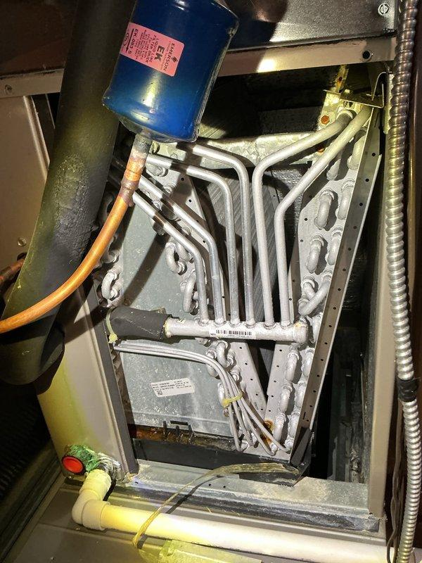 Performed comprehensive air conditioner tune-up maintenance under active service contract. Inspected and photographed return air filter showing dust accumulation along bottom edge; documented HVAC equipment including air handler unit and ductwork connections. Accessed interior components of system to inspect heat exchanger coils, capacitor, and associated electrical connections. All components found operating within normal parameters with no deficiencies requiring immediate attention. System confirmed functioning properly upon completion of routine maintenance procedures.