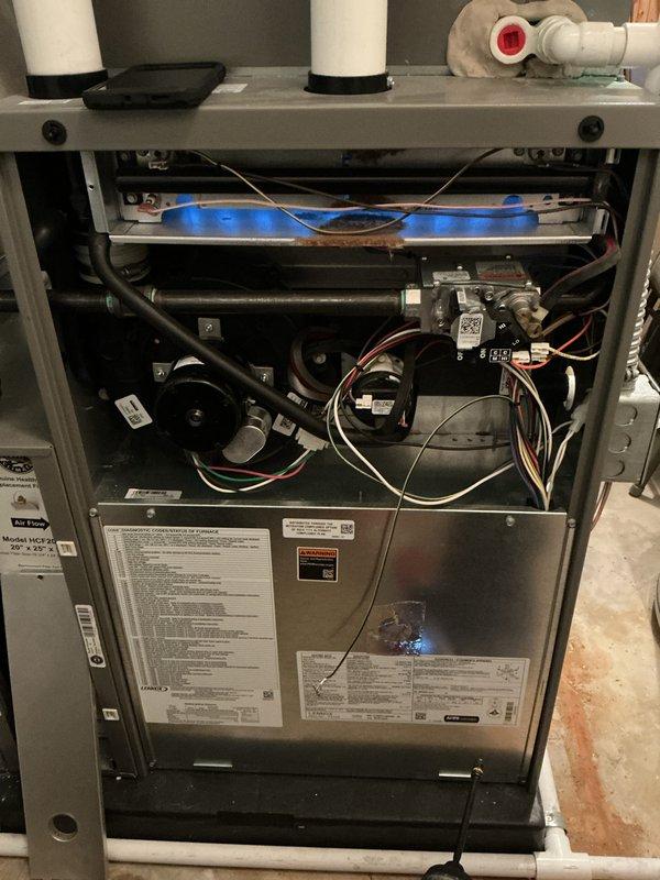 Completed annual Air Care Cooling maintenance inspection on residential HVAC system. Accessed furnace unit, inspected burner assembly and heat exchanger, verified proper operation of all components, and replaced dirty air filter with new unit. Documented equipment condition with photographs showing filter housing assembly and furnace interior components including burner, gas piping, electrical connections, and vent system.