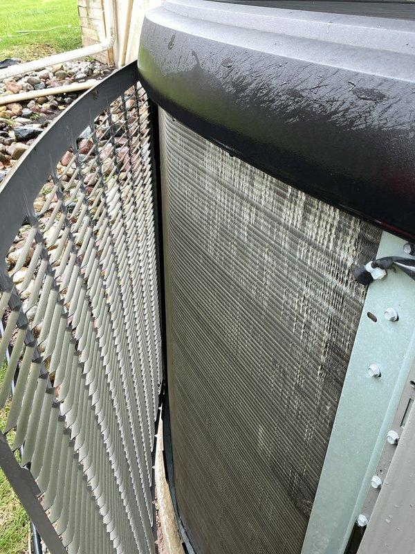 Completed annual maintenance on Lennox SL18XC1-030 outdoor condensing unit containing HFC-410A refrigerant. Inspected manufacturer specifications and confirmed proper labeling. Observed significant debris accumulation and discoloration on condenser coils, particularly on intake side, with visible buildup of leaves, pollen, and environmental contaminants between fins. Documented equipment condition through photographs showing operational unit with weathering consistent with outdoor exposure.