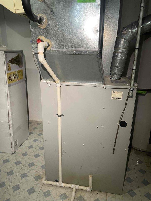 Conducted estimate consultation for replacement of 26-year-old furnace unit located in basement utility room. Assessed existing gray metal furnace with associated ductwork, PVC condensate drain line, and flexible duct connections to provide equipment replacement options and pricing for homeowner consideration.