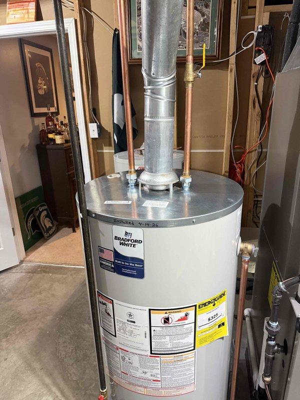 Installed a new 50-gallon Bradford White tanked water heater in residential basement utility room. Connected copper supply piping with brass fittings and yellow-handled shut-off valves, installed galvanized metal vent pipe with proper securing bands, and completed all electrical reconnections. Mechanical permit obtained and all work performed to code specifications.