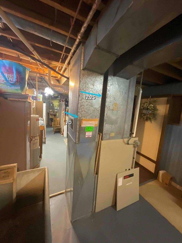 Conducted on-site assessment of 26-year-old residential furnace system located in basement area for replacement estimate. Documented existing equipment configuration, including current HVAC unit positioning relative to structural support column, clearance measurements, and existing ductwork connections. Captured detailed measurements and photographic documentation of installation space, noting copper piping routes, metallic ductwork elbows, and available clearances for new equipment installation. Evaluated basement access points, ceiling height with exposed joists, and concrete floor conditions to determine optimal replacement unit specifications and installation requirements for future summer 2026 replacement appointment.