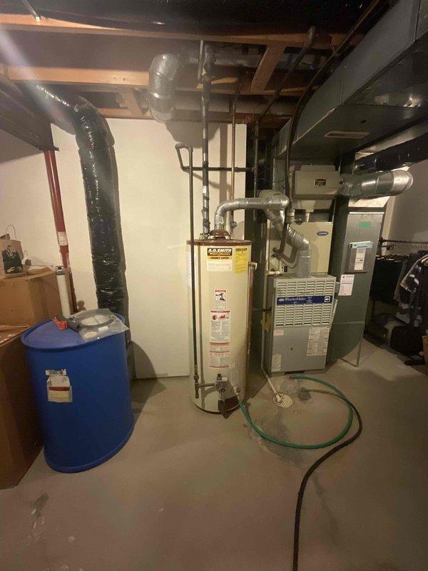 Provided estimate for water heater replacement in basement utility area. Assessed existing A.O. Smith water heater installation alongside blue pressure tank and Carrier HVAC system. Customer requested quote for standard water heater replacement, with venting configuration requiring determination between power vent or natural draft application based on current setup evaluation.