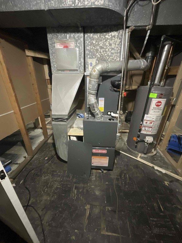 Provided estimate for complete replacement of basement-located natural gas furnace and hot water tank damaged by flooding. Both units less than one year old but rendered inoperable due to water damage. Assessment included evaluation of existing Goodman furnace system, cylindrical water heater unit, associated ductwork, venting systems, and utility connections in basement mechanical room with exposed joists and unfinished walls.