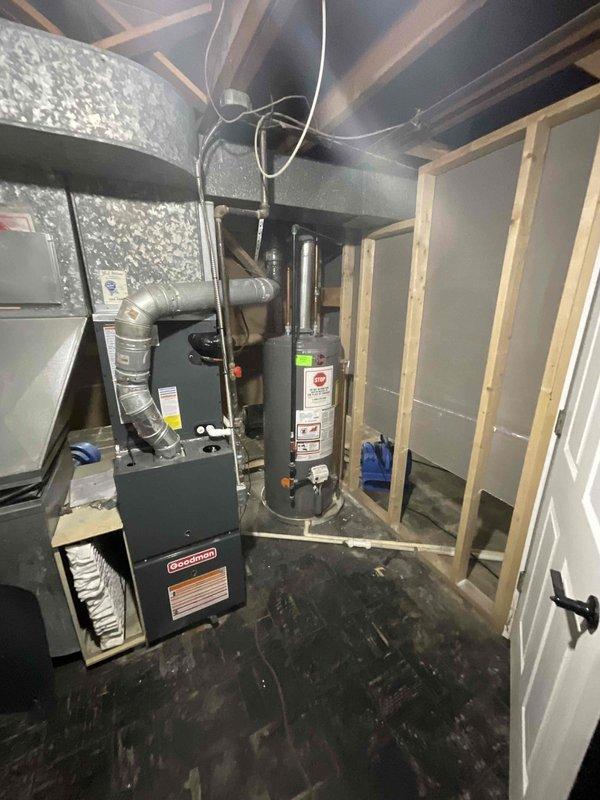 Provided estimate for complete replacement of basement-located natural gas furnace and hot water tank damaged by flooding. Both units less than one year old but rendered inoperable due to water damage. Assessment included evaluation of existing Goodman furnace system, cylindrical water heater unit, associated ductwork, venting systems, and utility connections in basement mechanical room with exposed joists and unfinished walls.