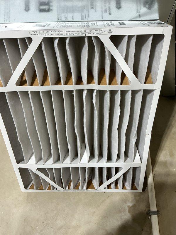 Completed annual cooling maintenance on HVAC air handler unit. Accessed interior cabinet and inspected A-frame evaporator coil assembly, noting light dust accumulation on serpentine tubing surfaces. Verified refrigerant line connections on suction and liquid lines with proper copper line integrity. Inspected filter drier component with manufacturer labeling intact and properly mounted. Checked condensate drain system with white PVC piping in place and functioning. Replaced air filter with clean pleated media filter showing proper accordion-fold construction and structural support framework. All electrical connections and wiring inspected and found secure. Unit operational and ready for cooling season.