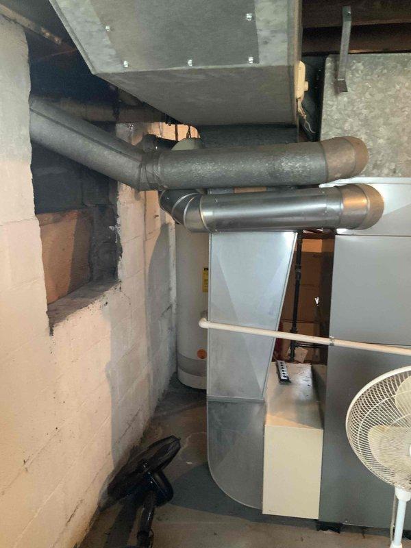 Performed estimate for replacement of 20-year-old furnace system in residential basement mechanical room. Assessed existing greenish-gray furnace unit with connected galvanized ductwork, humidifier accessory, and air handler components showing age-related wear and debris accumulation. Documented current HVAC configuration including horizontal duct runs, concrete utility space layout, and auxiliary equipment to provide comprehensive replacement quote and present available promotional offerings for comparison with other contractors.