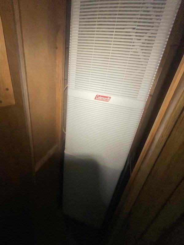 Provided estimate for new air conditioning system installation in a mobile home or RV application. Assessed the installation location, which features a narrow interior space with wooden panel framing designed to accommodate a Coleman heating and cooling unit. Evaluated the confined vertical space and existing infrastructure to determine proper equipment sizing and installation requirements for the new HVAC system.