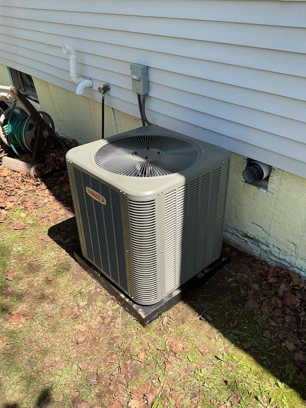 Completed installation of 2.5-ton Lennox air conditioning system with matching evaporator coil on left side of residential property. Unit positioned on composite pad against exterior wall with proper clearances, electrical disconnect box mounted to siding, and refrigerant lines connected. System commissioned and tested for proper operation, with all electrical connections completed per code requirements.