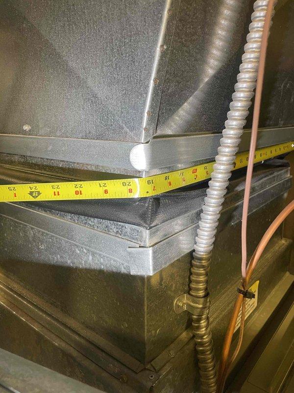 Conducted on-site evaluation for central air conditioning system replacement at owner-occupied side-by-side condo unit. Existing AC system is 25 years old, dating from 2001, and customer is exploring replacement options when promotional pricing becomes available. Performed comprehensive assessment of current HVAC infrastructure, including detailed measurements of existing ductwork dimensions in attic space, documenting 19-24 inch duct sections. Inspected air handler unit, condensate drain pan with seasonal operation markings, and evaluated flexible metallic ductwork connections. Photographed existing system components, insulation conditions, and mechanical room layout to support equipment sizing and replacement recommendations. Property access note: house number located over garage door.