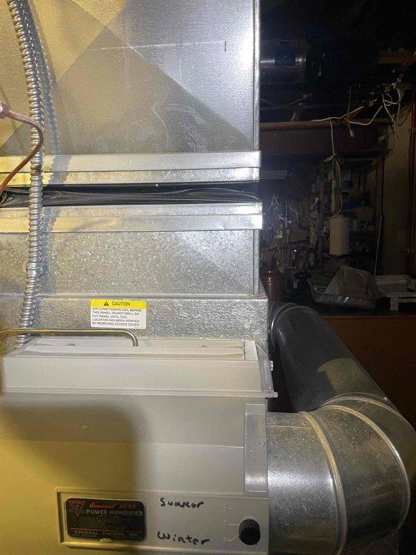 Conducted on-site evaluation for central air conditioning system replacement at owner-occupied side-by-side condo unit. Existing AC system is 25 years old, dating from 2001, and customer is exploring replacement options when promotional pricing becomes available. Performed comprehensive assessment of current HVAC infrastructure, including detailed measurements of existing ductwork dimensions in attic space, documenting 19-24 inch duct sections. Inspected air handler unit, condensate drain pan with seasonal operation markings, and evaluated flexible metallic ductwork connections. Photographed existing system components, insulation conditions, and mechanical room layout to support equipment sizing and replacement recommendations. Property access note: house number located over garage door.