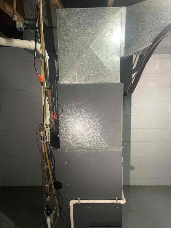 Conducted comprehensive evaluation of existing HVAC system for replacement estimate. Existing furnace approximately fifteen years old and nearing end of serviceable life. Assessed current three-unit stacked configuration including furnace and air conditioning components with associated refrigerant lines, electrical connections, and condensate drainage system. Documented existing equipment specifications, noting filter size requirements of 30x16x1 and current installation layout in basement mechanical room. Photographed complete system setup including copper refrigerant piping, electrical conduit routing, PVC condensate drain lines, and flexible ductwork connections to provide accurate replacement specifications. Evaluated installation space constraints and existing infrastructure to determine optimal replacement equipment sizing and configuration recommendations for complete furnace and AC system upgrade.
