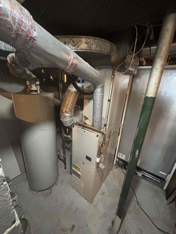 Provided estimate for complete HVAC system replacement including furnace and air conditioning unit under promotional offer. Existing 20+ year old equipment located in basement mechanical room with natural gas furnace currently operational but outdoor AC condenser unit non-functional. Assessment included evaluation of basement-installed furnace with existing ductwork, water heater proximity, and gas line configuration, as well as exterior condenser unit positioned on concrete pad adjacent to brick foundation with landscaping considerations for replacement access and installation.