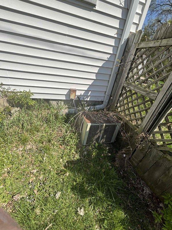 Provided estimate for complete air conditioning system replacement for non-operational 30+ year old outdoor unit. Assessed existing outdoor condenser positioned along exterior wall near wooden lattice fence and evaluated interior components including ductwork and furnace connections compatible with natural gas heating system. Documented current equipment configuration and site conditions to prepare comprehensive replacement proposal for new cooling system.
