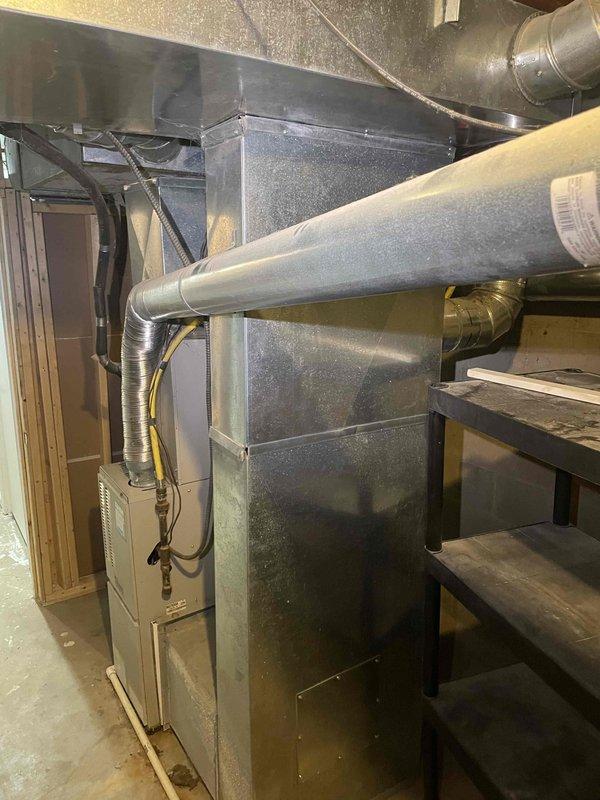 Provided comprehensive estimate for complete HVAC system replacement in basement location. Assessed existing 21-year-old natural gas furnace and air conditioning system, both non-operational. Evaluated current ductwork configuration including metal supply and return ducts with flexible insulated connections throughout unfinished basement space. Documented equipment specifications, existing installation layout, and system requirements for furnace and air conditioner replacement under promotional offer. Reviewed access considerations, utility connections, and necessary modifications for new equipment installation.