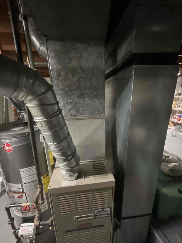 Conducted site evaluation for air conditioning replacement estimate in basement mechanical room. Assessed existing HVAC system configuration including furnace unit, ductwork layout, and available space for new equipment installation. Documented current system setup with metallic air handler, existing supply and return plenum connections, and flexible duct routing to determine compatibility requirements for proposed AC unit replacement.