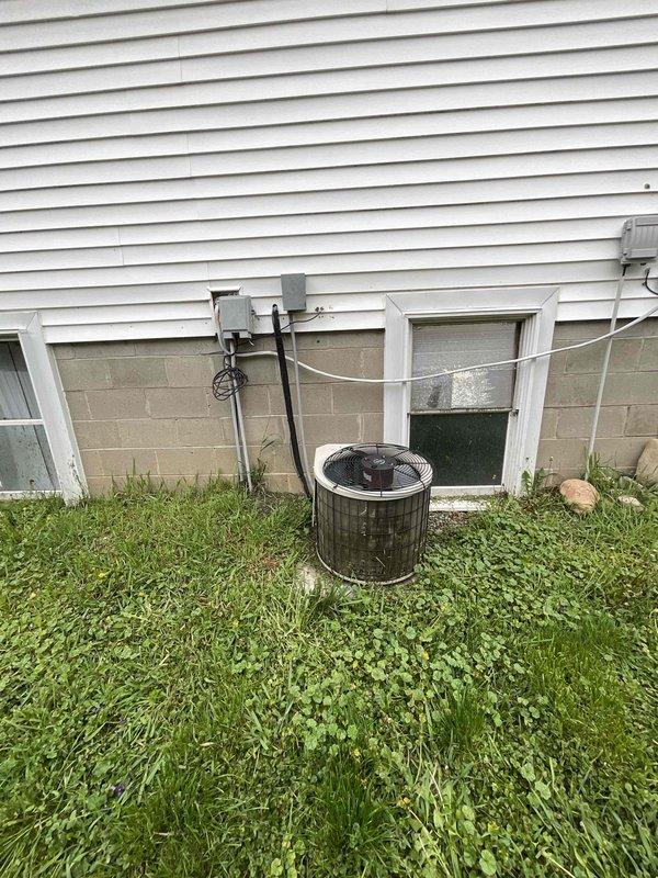 Performed comprehensive assessment of existing 16-20 year old HVAC system with non-functional AC condenser compressor due to age-related deterioration and weather corrosion. Inspected outdoor condensing unit with cylindrical configuration, noting advanced wear on compressor components and external housing. Evaluated indoor furnace and air handler equipment located in basement utility area, examining ductwork connections, gas line installations, and electrical service. Documented complete system configuration including water heater proximity, PVC condensate drainage, flexible gas connections, and electrical disconnect box placement at exterior wall. Provided comprehensive estimate options for full system replacement including new furnace and AC condenser unit, as well as alternative pricing for condenser-only replacement to meet immediate seasonal cooling needs.