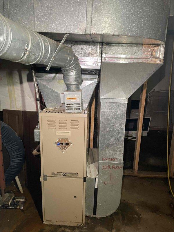 Completed comprehensive replacement estimate for residential HVAC system including 15-year-old York furnace and hot water heater. Inspected existing furnace installation, ductwork configuration, and utility room layout in basement area. Documented current equipment specifications, ventilation system, and spatial requirements for replacement units through detailed photography of furnace, metalwork plenum, and duct routing to provide accurate pricing and installation planning for customer.