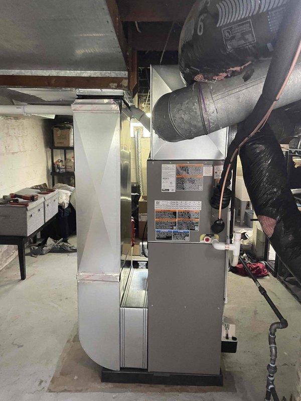 Completed full HVAC system installation including a 70,000 BTU furnace with liner and 2-ton air conditioning unit with right-side configuration. Installed new electrical circuit to support the system and ran all necessary ductwork connections in basement mechanical room. Mounted exterior condensate drain lines with PVC piping and cleanout access point on building exterior, securing all components to vinyl siding above foundation. Obtained mechanical and electrical permits prior to installation and documented completed work with photographs showing installed equipment and exterior penetrations.