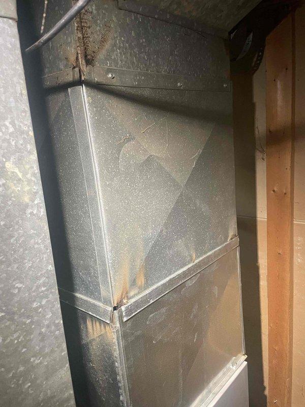 Conducted comprehensive assessment of existing HVAC system for full replacement estimate at homeowner-occupied single family residence. Documented current equipment condition including furnace/air handler unit with visible aging, metallic ductwork showing rust staining, oxidation at seams, and water damage patterns indicating potential system inefficiencies. Photographed all major components including rectangular metal ductwork with dust accumulation, flexible ducting connections, condensate drain pan, and electrical wiring configuration to provide accurate replacement specifications for complete system installation.