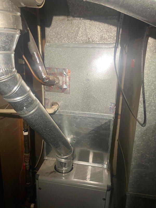 Conducted comprehensive assessment of existing HVAC system for full replacement estimate at homeowner-occupied single family residence. Documented current equipment condition including furnace/air handler unit with visible aging, metallic ductwork showing rust staining, oxidation at seams, and water damage patterns indicating potential system inefficiencies. Photographed all major components including rectangular metal ductwork with dust accumulation, flexible ducting connections, condensate drain pan, and electrical wiring configuration to provide accurate replacement specifications for complete system installation.