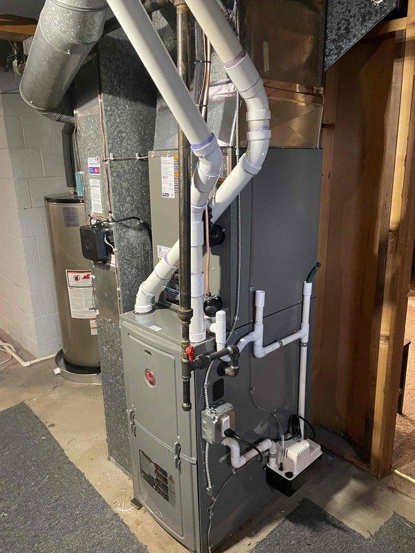 Successfully completed installation of a 2.5-ton air conditioning system with matching evaporator coil in residential basement mechanical room. Installed new dark gray air handler unit adjacent to existing beige furnace, connected white PVC condensate drainage lines, and integrated system with existing ductwork infrastructure including flexible insulated ducts. Exterior work included mounting new disconnect box on home's siding and routing refrigerant linesets and electrical connections through foundation wall. Verified proper refrigerant charge, tested system operation and airflow, and confirmed all electrical connections were secure. All work performed under mechanical permit with reconnection of electrical components completed separately.
