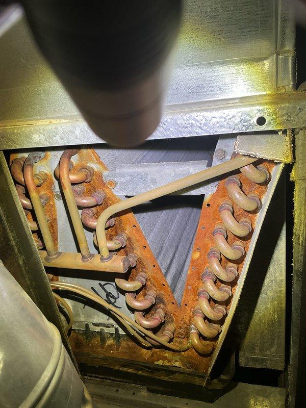 Completed annual cooling maintenance on Bryant HVAC system. Performed comprehensive inspection of evaporator coil assembly, ductwork connections, and refrigerant lines. Documented significant corrosion and rust buildup on evaporator coil copper tubing and metal collars, indicating advanced age and potential efficiency concerns. Inspected triangular A-coil configuration within metal framework, noting oxidation throughout parallel tube arrangement. Verified proper insulation placement behind coil assembly. Examined supply ductwork, refrigerant line connections, and electrical wiring routing. System operational at time of inspection. Photographed equipment condition for records. Recommend monitoring system performance closely and considering coil replacement due to extent of corrosion observed.