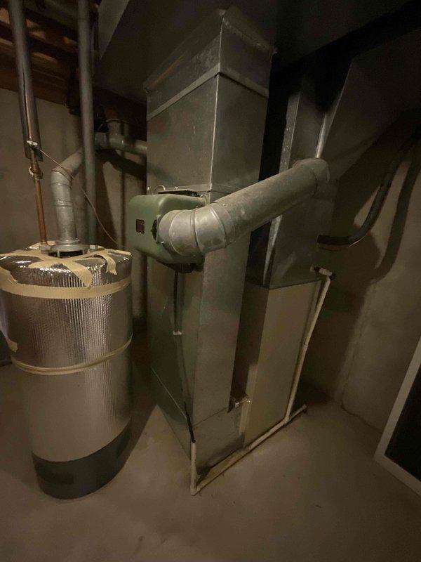 Conducted comprehensive assessment of existing HVAC system in basement mechanical room for complete furnace replacement estimate. System evaluation revealed aging furnace unit with connected humidifier component, metal ductwork, and plenum assembly showing typical wear consistent with end-of-service-life equipment. Documented current installation configuration including duct connections, copper piping, and mechanical room layout to provide accurate replacement specifications and equipment sizing recommendations for new high-efficiency system installation.