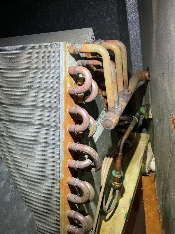 Completed comprehensive air conditioning maintenance tune-up including full system inspection and performance evaluation. Inspected evaporator coil assembly and heat exchanger components, noting copper tubing connections showing typical oxidation consistent with normal system operation. Verified all refrigerant line connections, checked fin condition on coil assembly, and confirmed proper installation of gasket seals and insulation materials. System operational and functioning within normal parameters.