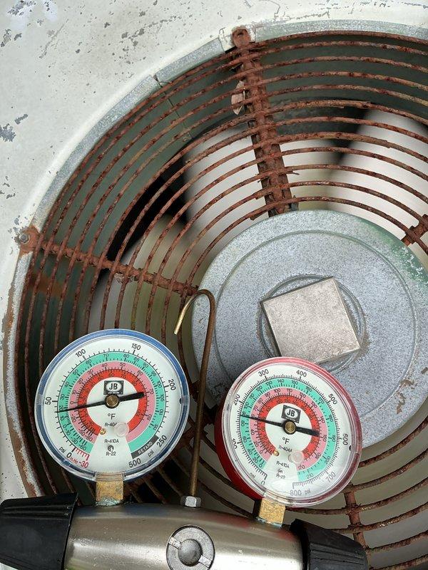 # HVAC Maintenance - ACM

Completed comprehensive spring tune-up on 49-year-old forced air air conditioning system. Upon arrival, system was operating normally. Performed standard preventive maintenance protocol including visual inspection of outdoor condensing unit, which revealed significant age-related corrosion on coil assembly and metal banding, consistent with equipment of this vintage.

Connected manifold gauge set to service ports and recorded operating pressures and temperatures. Evaluated refrigerant charge levels and system performance parameters. Inspected condenser coil for debris accumulation and airflow restrictions. Examined electrical connections, contactors, and capacitor condition. Verified proper operation of condenser fan motor and compressor.

Checked refrigerant line insulation and service valve integrity. Assessed condensate drain line for proper drainage. Inspected mounting hardware and cabinet condition, noting exterior weathering and rust formation on metal c