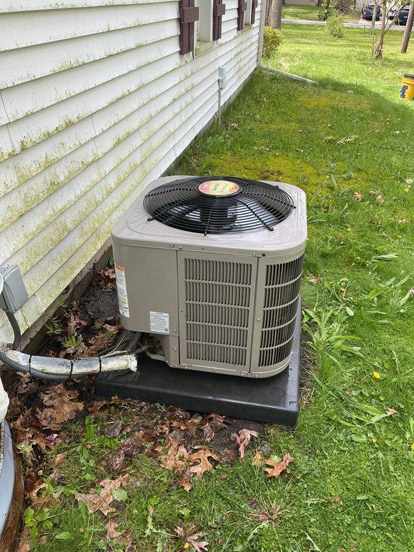 Completed seasonal air conditioning maintenance and tune-up on outdoor condensing unit as part of annual service plan. System was operational upon arrival. Performed comprehensive inspection of beige/tan condenser unit including examination of fan motor assembly, condenser coils with vertical fins, electrical connections, and refrigerant levels. Verified proper operation of compressor and condenser fan with black circular guard. Inspected unit mounting on polymer pad for stability and proper drainage. Checked PVC condensate line for clear flow and proper drainage away from foundation. Cleaned debris including leaves and organic matter from around unit base and verified adequate clearance from house siding for proper airflow. System tested and confirmed operating within normal parameters, ready for cooling season.