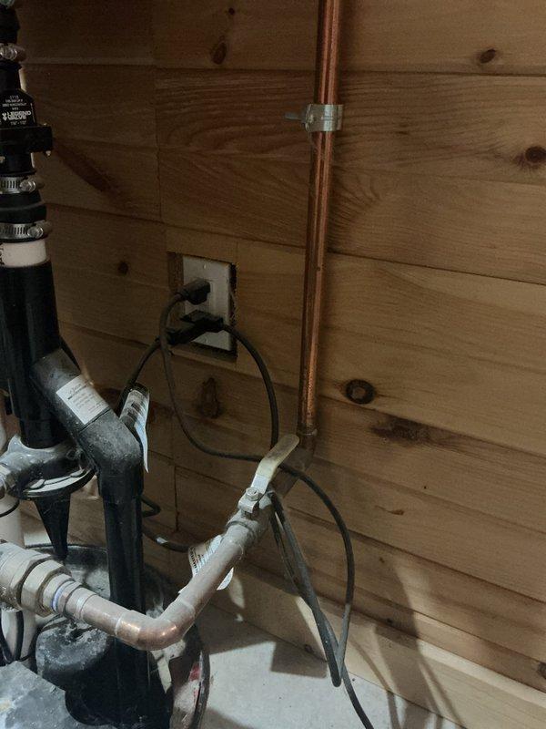 Responded to service call for reported water leak at base of standard tank water heater. Upon arrival, conducted thorough inspection of unit and surrounding plumbing connections. Examined tank integrity, temperature and pressure relief valve, drain valve, and all inlet/outlet connections for signs of active leakage or moisture accumulation. Inspected copper supply lines and PVC discharge piping for proper installation and secure mounting. Verified pump assembly operation and checked all connection points for potential leak sources. Documented existing conditions with photography showing water heater installation, piping configuration, and utility room setup for service records.