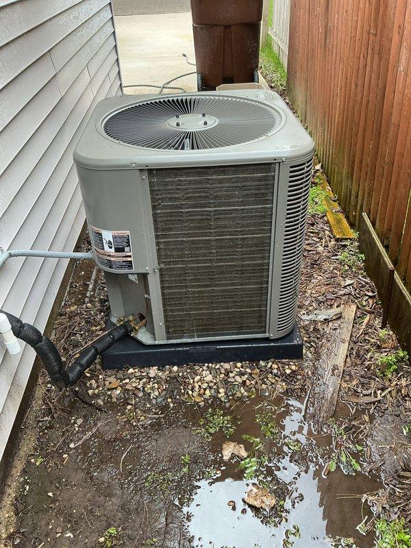 Completed ACM5/12-5 renewal maintenance on residential air conditioning unit located in side yard. Upon arrival, discovered heavily clogged air filter with excessive accumulation of dirt, dust, and debris throughout entire surface, significantly restricting airflow and reducing system efficiency. Removed and replaced contaminated filter with new unit per manufacturer specifications. Inspected outdoor condensing unit and surrounding area, noting wet ground conditions and proper drainage around equipment pad. Verified unit operation, airflow improvement, and proper system function following filter replacement. Documented equipment condition with photographs for service records.